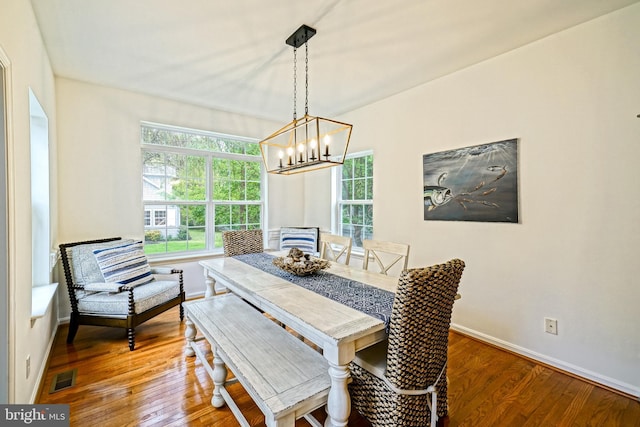 dining space with baseboards, visible vents, wood finished floors, and a notable chandelier