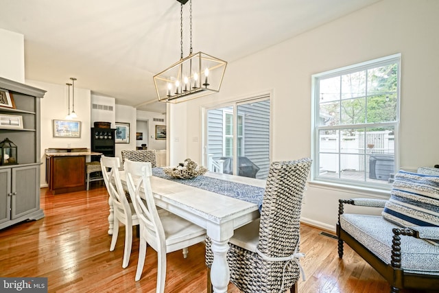 dining area featuring an inviting chandelier, baseboards, light wood-style flooring, and visible vents