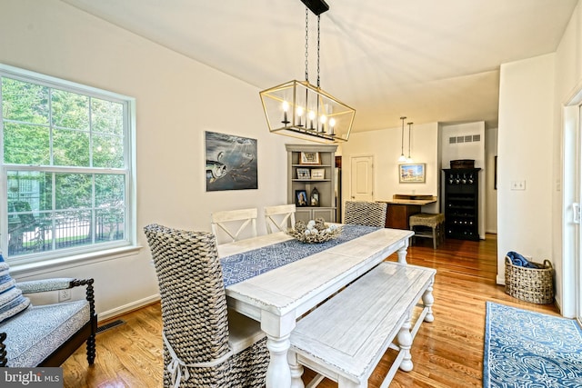 dining room with visible vents, an inviting chandelier, a healthy amount of sunlight, and light wood finished floors