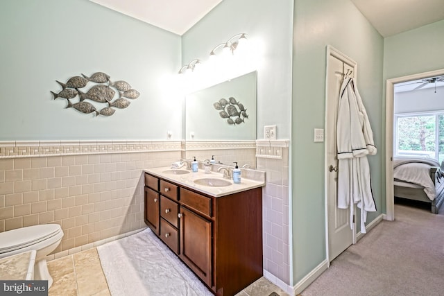 ensuite bathroom with a sink, tile walls, ensuite bath, and double vanity
