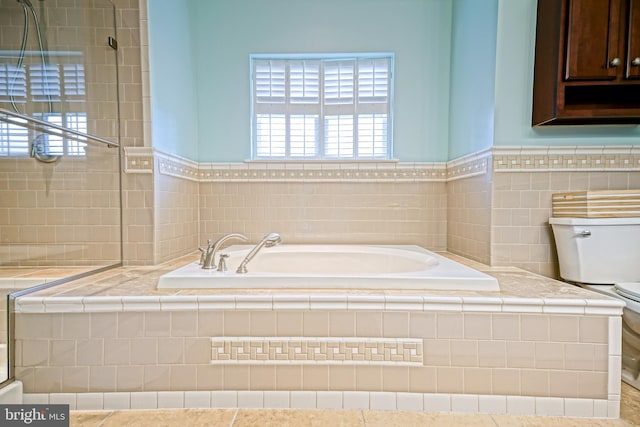 full bathroom featuring wainscoting, tile walls, a garden tub, and toilet