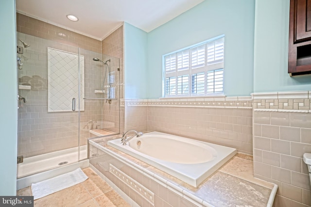 bathroom with tile walls, a wainscoted wall, a bath, and a stall shower