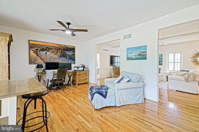 living area with ceiling fan, wood finished floors, and visible vents