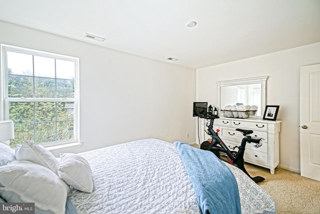 bedroom with visible vents, multiple windows, and light colored carpet