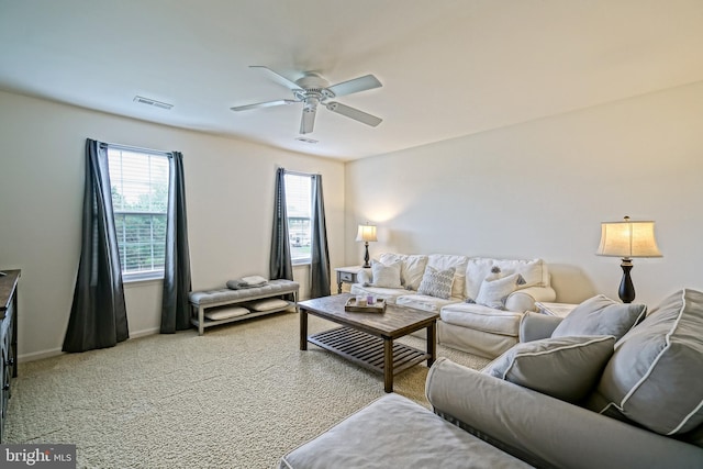 living room featuring light colored carpet, ceiling fan, visible vents, and baseboards