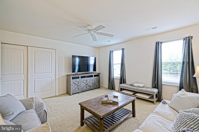 living area with visible vents, ceiling fan, and light carpet
