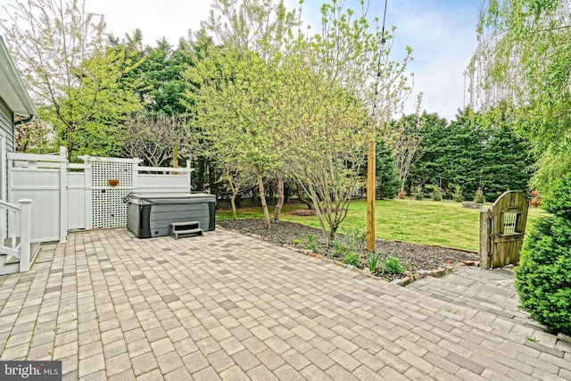 view of patio with a hot tub and fence
