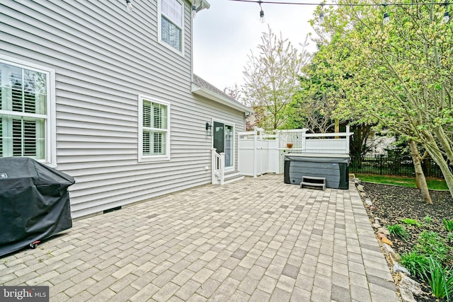 view of patio with a hot tub, fence, and area for grilling
