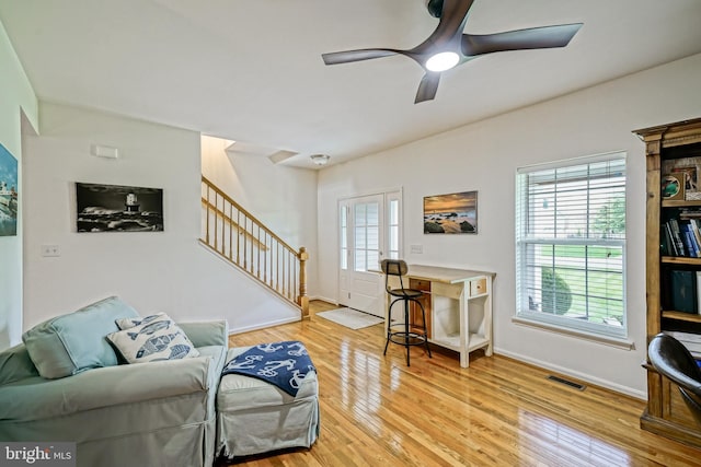 living room featuring baseboards, ceiling fan, wood finished floors, and stairway