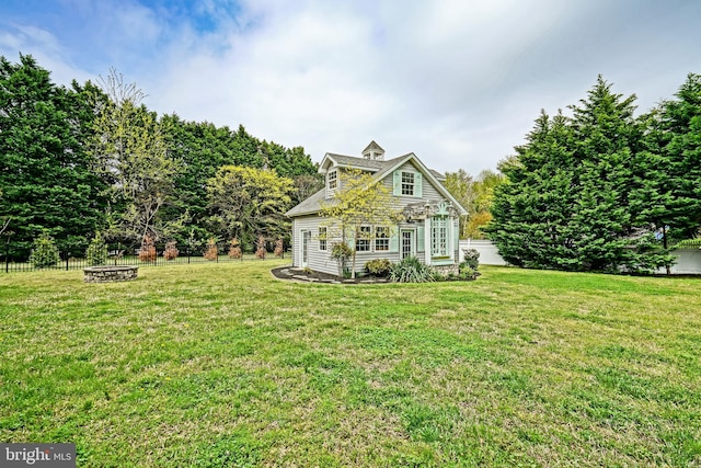 view of front of house with fence, a front yard, and an outdoor fire pit