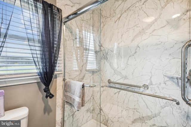 bathroom featuring toilet and a marble finish shower