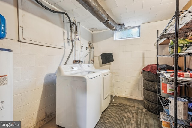 laundry room featuring water heater, concrete block wall, washer and clothes dryer, and laundry area