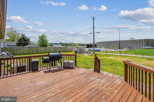 wooden terrace with a grill, fence, and a lawn