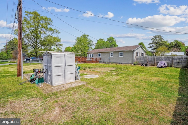 view of yard with a deck, an outdoor structure, fence, cooling unit, and a shed