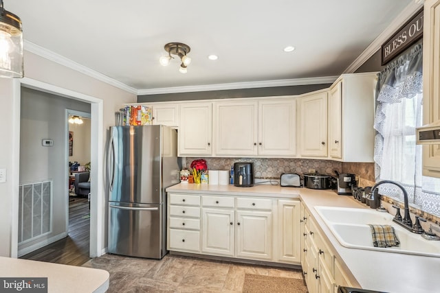 kitchen featuring a sink, tasteful backsplash, crown molding, visible vents, and freestanding refrigerator