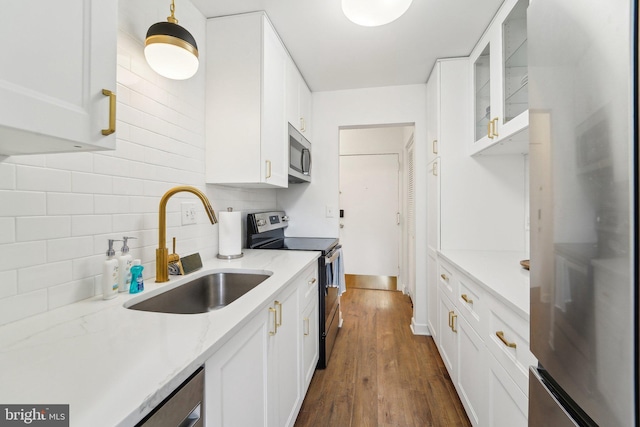 kitchen with a sink, stainless steel appliances, white cabinetry, backsplash, and glass insert cabinets