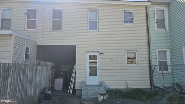 rear view of house featuring fence and entry steps