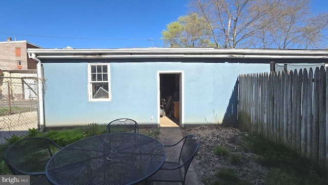 rear view of property with stucco siding and fence