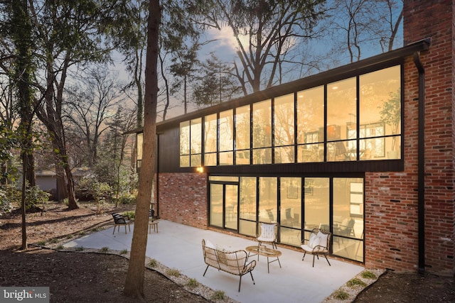 rear view of house with brick siding and a patio area