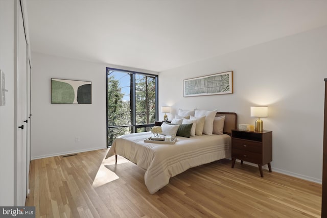 bedroom featuring baseboards, floor to ceiling windows, and light wood-style floors
