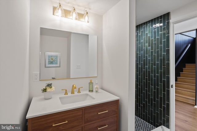 full bath featuring a tile shower and vanity