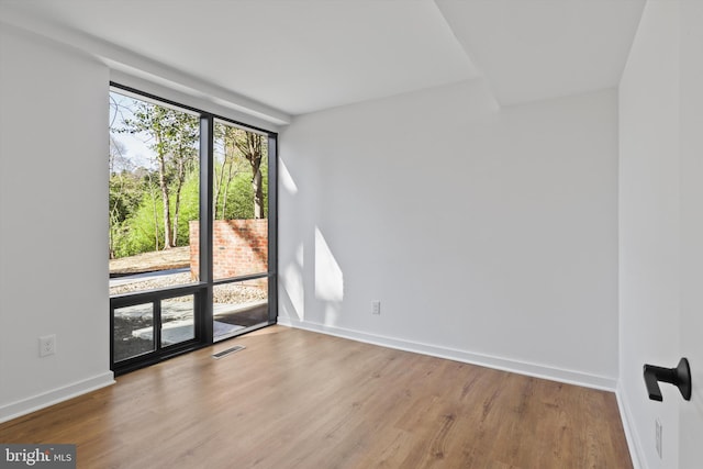spare room featuring baseboards, wood finished floors, and visible vents