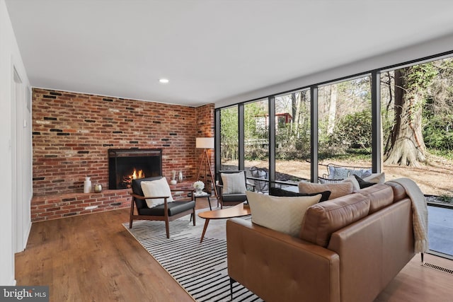 living room with wood finished floors, a wealth of natural light, brick wall, and visible vents