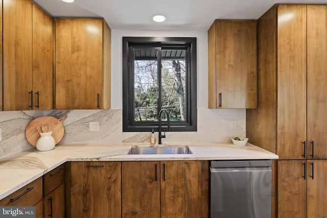 kitchen with brown cabinets, backsplash, stainless steel dishwasher, a sink, and light stone countertops
