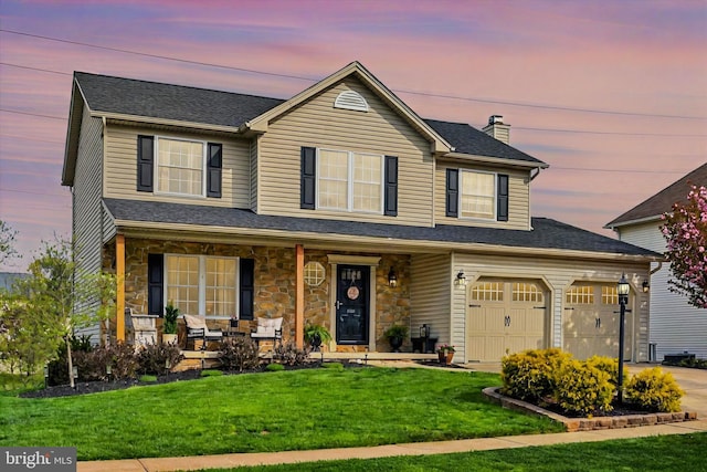 view of front of house featuring covered porch, a lawn, driveway, stone siding, and a chimney
