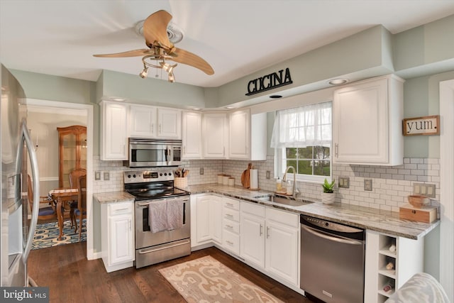 kitchen with light stone counters, white cabinetry, a sink, appliances with stainless steel finishes, and ceiling fan