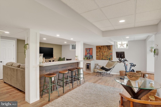 bar featuring bar, light wood-style floors, baseboards, recessed lighting, and a paneled ceiling