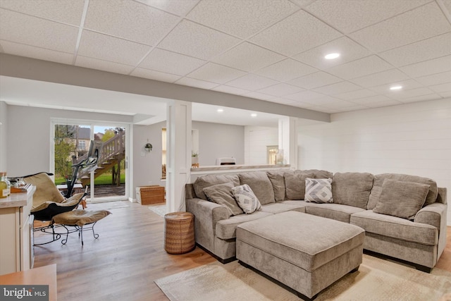 living area with a drop ceiling, recessed lighting, and light wood finished floors