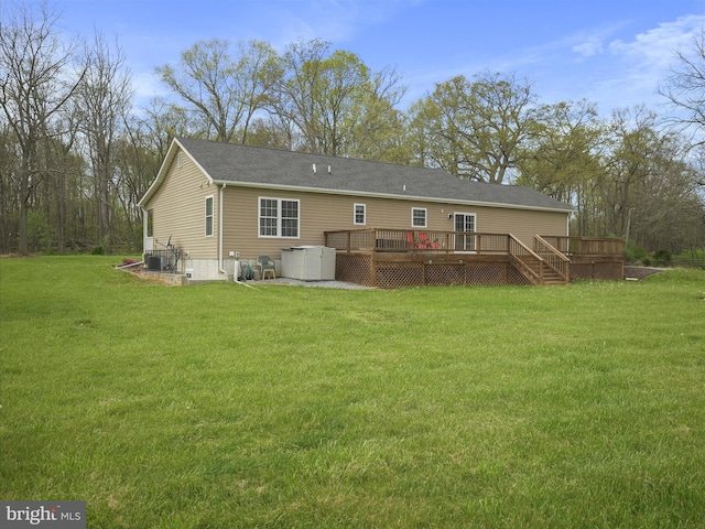 rear view of property with a yard, central air condition unit, and a deck