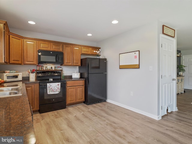 kitchen with black appliances, light wood finished floors, dark countertops, and brown cabinetry