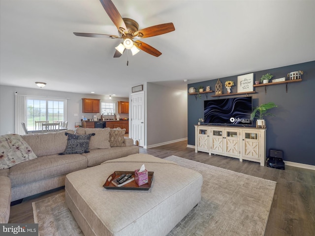 living room featuring baseboards, wood finished floors, and a ceiling fan