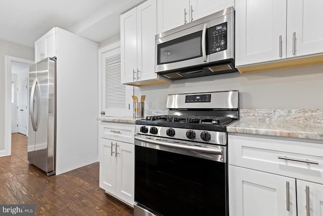 kitchen featuring dark wood-type flooring, white cabinetry, light stone counters, and stainless steel appliances
