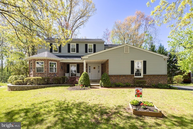 traditional home with brick siding, covered porch, and a front yard