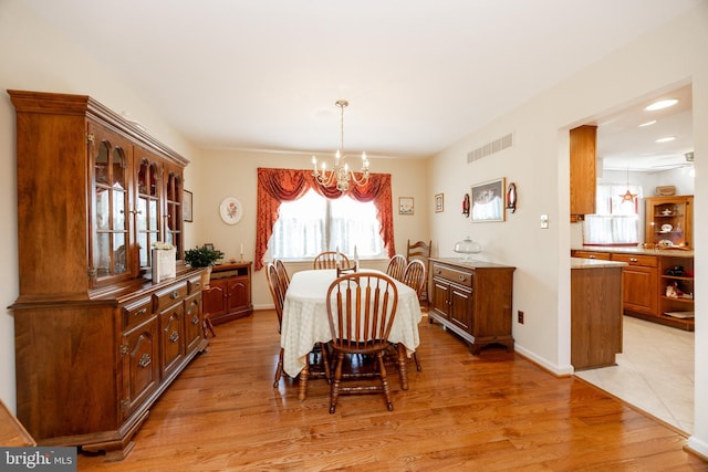 dining space featuring baseboards, visible vents, light wood-style flooring, and a notable chandelier
