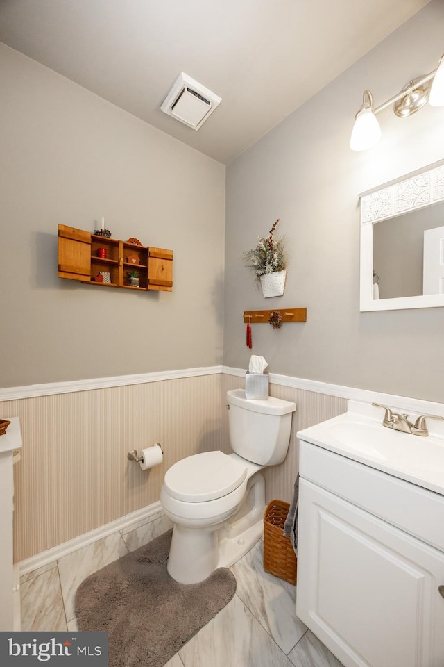 bathroom featuring vanity, marble finish floor, wainscoting, and toilet