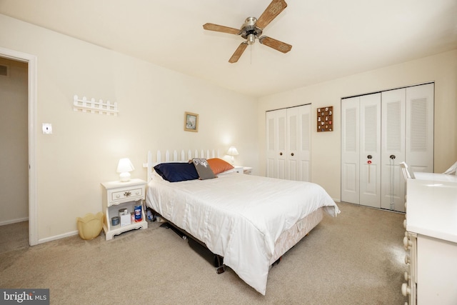 bedroom featuring two closets, a ceiling fan, baseboards, and light colored carpet