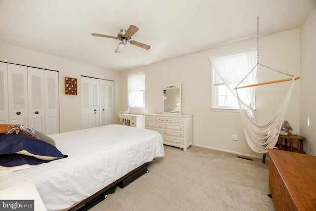 bedroom featuring light colored carpet, multiple closets, multiple windows, and visible vents