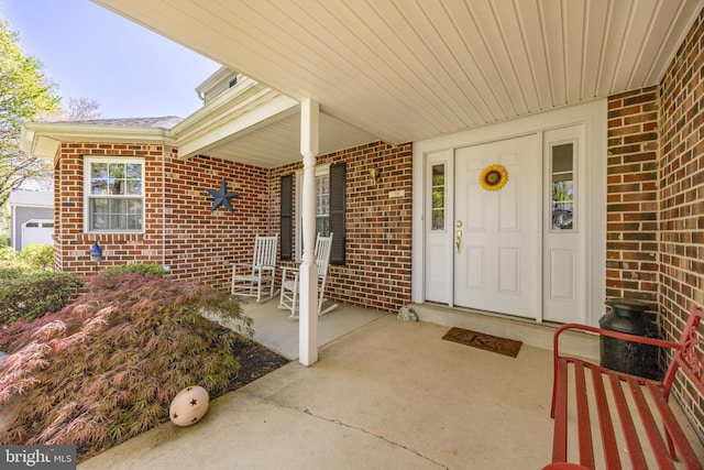 entrance to property featuring covered porch and brick siding