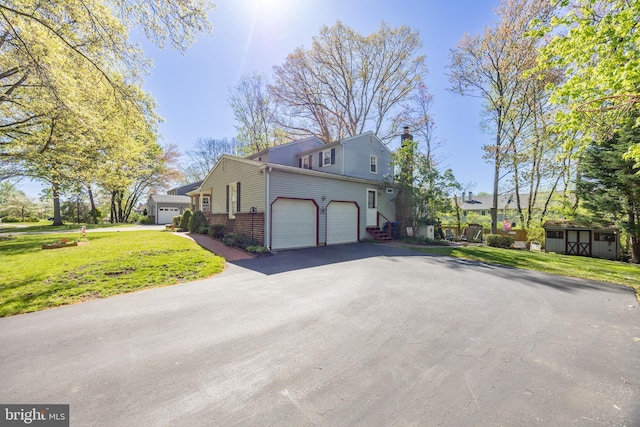 view of side of home featuring brick siding, an attached garage, aphalt driveway, and a yard
