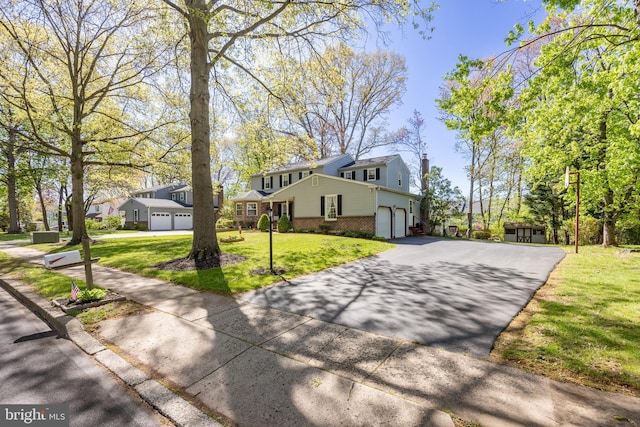 view of front of home with an attached garage, a front yard, driveway, and brick siding