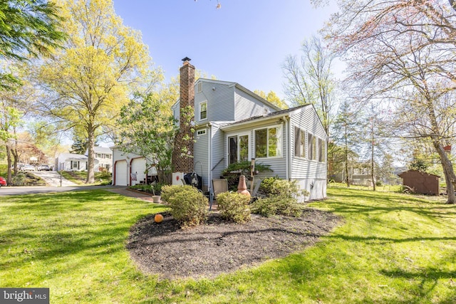 view of home's exterior with a lawn, a detached garage, and a chimney