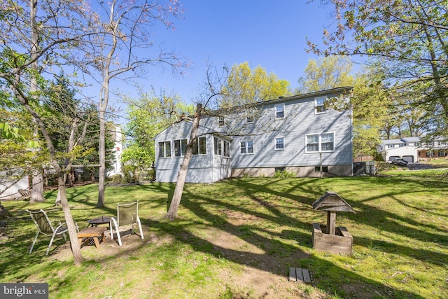 back of house featuring a yard, a chimney, and an outdoor fire pit