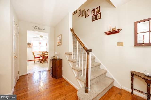stairs featuring baseboards, ceiling fan, and wood finished floors