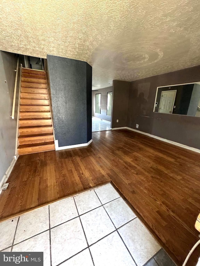 7437 Berkshire Rd, Baltimore, MD 21224 - unfurnished living room with wood finished floors, baseboards, stairs, and a textured ceiling