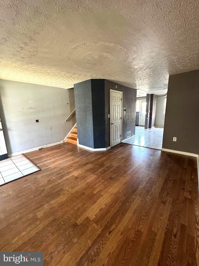 7437 Berkshire Rd, Baltimore, MD 21224 - unfurnished living room with wood finished floors, a textured ceiling, baseboards, and stairs
