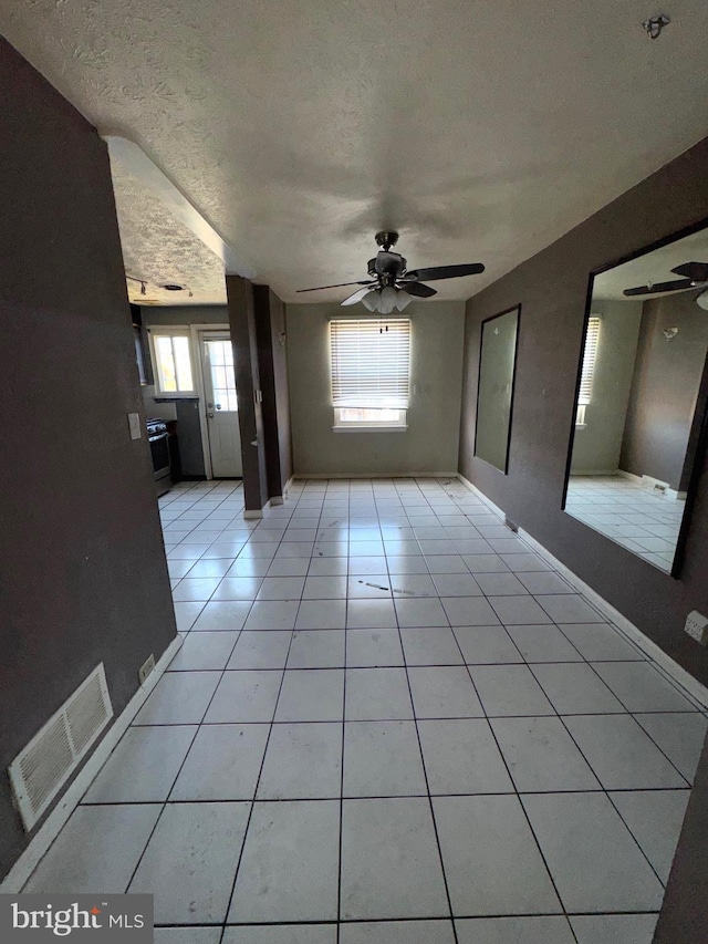 7437 Berkshire Rd, Baltimore, MD 21224 - unfurnished living room with ceiling fan, plenty of natural light, light tile patterned flooring, and a textured ceiling